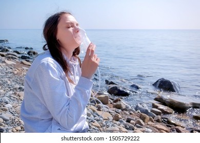 Young Sick Woman Uses Nebulizer On Seaside. Inhaling Inhaler Mask. Fibrosis Cystic Copd And Treatment Inhaler. Asthma Pulmonary Respiratory Breath Problem And Cure. Painkiller Sedative Gas Oxygen.