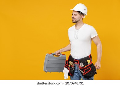 Young side view confident employee handyman man 20s in protective helmet hardhat tool case box walk isolated on yellow background Instruments accessories renovation apartment room Repair home concept