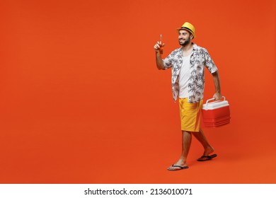 Young side view happy cool tourist man 20s in beach shirt hat hold beer bottle alcohol cooler box fridge isolated on plain orange background studio portrait. Summer vacation sea rest sun tan concept