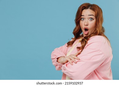 Young Side View Indignant Redhead Chubby Overweight Woman 30s With Curly Hair In Pink Shirt Casual Clothes Hold Hands Crossed Folded Isolated On Pastel Blue Background Studio. People Lifestyle Concept