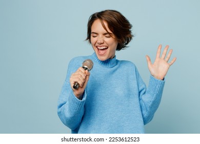 Young singer happy caucasian woman wear knitted sweater sing song in microphone raise up hand close eyes isolated on plain pastel light blue cyan background studio portrait. People lifestyle concept - Powered by Shutterstock