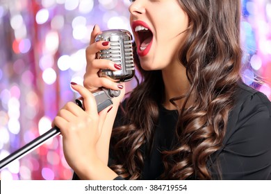 Young Singing Woman With Retro Microphone Against Bright Colourful Background, Close Up