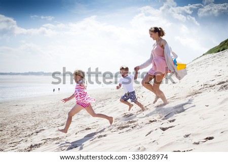 Young single parent family running down the sanddunes at the beach.