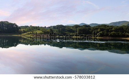 A Young single scull rowing competitor paddles on the tranquil lake
