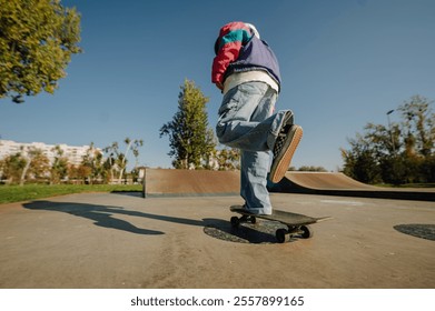 Young skateboarder balancing on one leg while riding his skateboard in a skatepark on a sunny day, showing balance and skill - Powered by Shutterstock