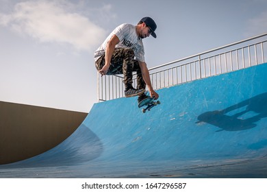 Young Skateboarder Does A Trick Called Boneless On The Ramp Of A Skate Park