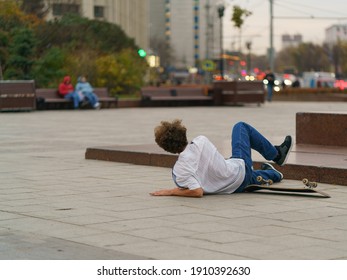 Young skateboarder performs a trick on a city street in day. Young man is jumped. He fell. Extreme sports is very popular among youth. Back, rear view. He  struck one in the fall - Powered by Shutterstock