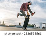 Young skateboarder skillfully jumps on his longboard at a vibrant skate park during sunset, capturing the energy and movement of this action-packed sport