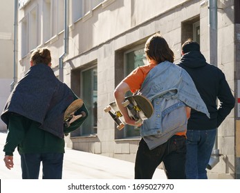 Young Skateboarders Go Home At City Street In Spring Day. They Carry Out Thier Skateboards. Extreme Sports Is Very Popular Among Youth. Sports Season Are Closed Due To Coronavirus Epidemic. Backs 