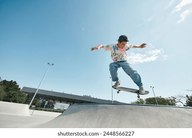 A young skater boy confidently rides his skateboard up the side of a ramp in an outdoor skate park on a sunny summer day. - Powered by Shutterstock