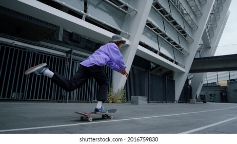 Young skater boy riding on skateboard in urban view. Active hipster practicing extreme ride on boardwalk in city stadium. Sporty skateboarder accelerating on skate board outdoors in slow motion. - Powered by Shutterstock