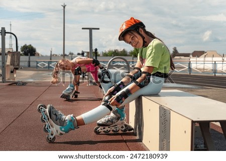 Young skater girl putting on protective shin guards and knee pads for skating. children female rollerblader preparing for a ride in skatepark in summer