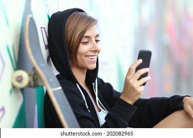 Young skater happy teen girl using a smart phone with a blurred graffiti wall in the background         - Powered by Shutterstock