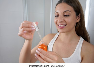 Young Skin Care Routine. Beautiful Girl Applying A Vitamin C Booster Antioxidant Ascorbic Acid Anti Aging Serum To Her Face While Holding A Pipette In Her Hand.