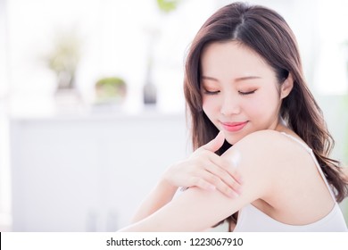 Young skin care woman applying body lotion on arm and shoulder at home