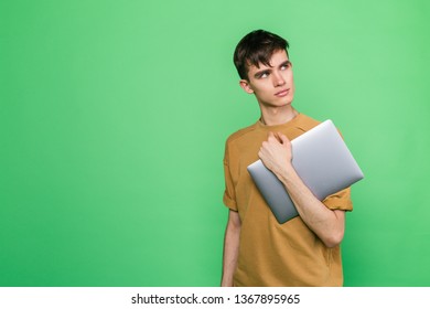 Young Skinny Guy Holding A Laptop Standing On A Green Background