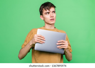 Young Skinny Guy Hugged His Laptop Standing On A Green Background