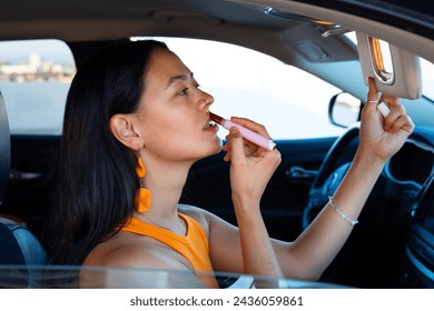 Young and Skinny South American Woman Applying Red Lipstick inside the Car, Los Angeles - Powered by Shutterstock