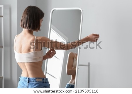 Young skinny woman in front of mirror at home. Anorexia concept Imagine de stoc © 