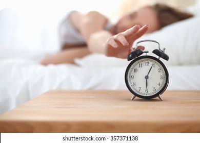 Young Sleeping Woman And Alarm Clock In Bedroom At Home