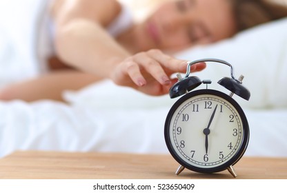 Young Sleeping Woman And Alarm Clock In Bedroom At Home