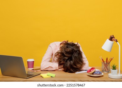 Young sleepy tired sad exhausted employee business woman wear casual shirt sit work at office with pc laptop put head on desk sleep isolated on plain yellow color background Achievement career concept