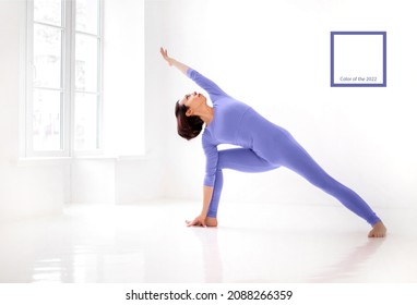 Young slender fit woman in violet long bodysuit performing yoga pose, isolated over white studio background. Healthy lifestyle, sport and fitness concept. Color of 2022 year, very peri
