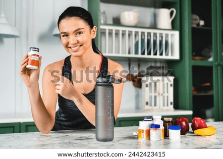 Young slim caucasian girl pointing at food supplements in the kitchen. Fiber and vitamins, Omega 3 for healthy hair nails and skin. Slimming and diet for burning calories