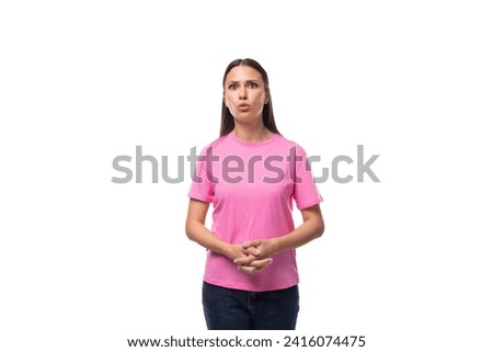 young slim european woman with black straight hair is dressed in a pink t-shirt on a studio background with copy space [[stock_photo]] © 