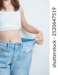 young slim female wearing big or oversize jeans, woman show healthy shape after weight loss. dieting, exercise, body fit and liposuction surgery concept