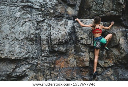 young slim muscular woman rockclimber climbing on tough sport route, searching, reaching and gripping hold. climber makes a hard move. outdoors rock climbing and active lifestyle concept