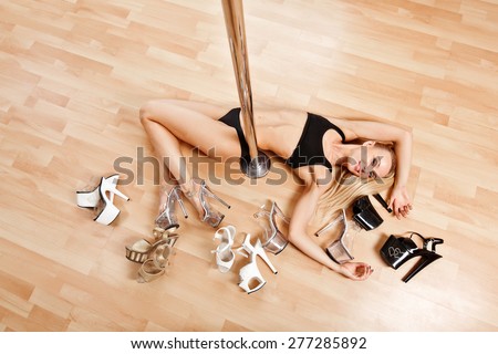 Young slim pole dance blond woman lies on floor near pool