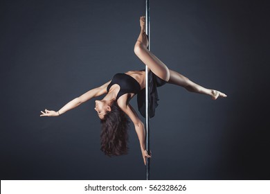 Young slim pole dance girl of asian appearance on a black studio background