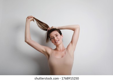 Young Slim Woman In Beige Body Showing Her Body Shape, Stretching Her Hair Up. Body Positive And Mental Health Concept.