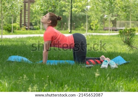 young slim woman practices yoga and stretching in nature in the park