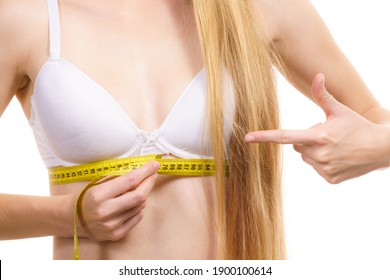 Young slim woman wearing bra with measure tape measuring her chest under breast. Bosom, brafitting and underwear concept.