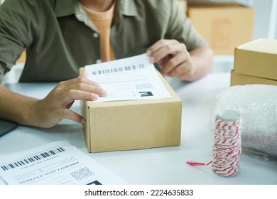 Young Small Business Entrepreneur Man, Online Store Onwer With Shelves Of Cardboard Boxes In The Background Packing Product In Mailing Box, Labeling Delivery Package For Shipping To Customer.