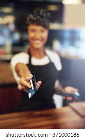 Young Small Business Owner Handing Back A Credit Card To A Customer After Processing A Payment, Focus To Her Hand And The Card