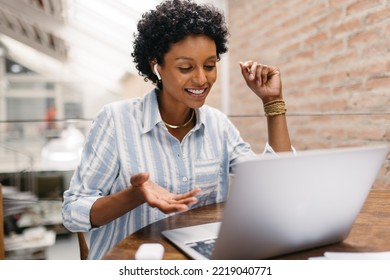 Young Small Business Owner Having An Online Meeting In A Warehouse. Female Entrepreneur Video Calling Her Business Partners On A Laptop. Happy Businesswoman Running An Online Startup.