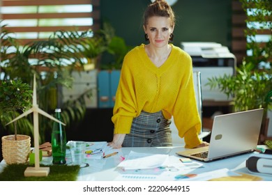 Young Small Business Owner Woman In Yellow Sweater With Laptop Standing In The Modern Green Office.