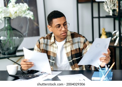 Young Smart Focused Hispanic Millennial Man, Freelancer Or Office Worker, Modern Stylish Guy, Sitting At His Work Desk, Analyzing Financial Documents, Doing Paperwork, Working In The Office