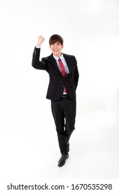 Young Smart Handsome Asian Man Business Office Wearing Suit Tie On White Background Look At Camera Walk Forward Fist Up Joy Success 