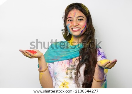 Young smart indian girl face coloured with gulal and hand full of color powder for festival of colours Holi, a popular hindu festival celebrated across india advertisement isolated white background