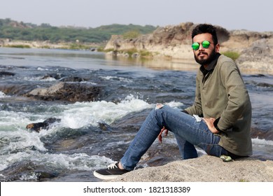 Young Smart Indian Man sitting at River Side, looking at the camera