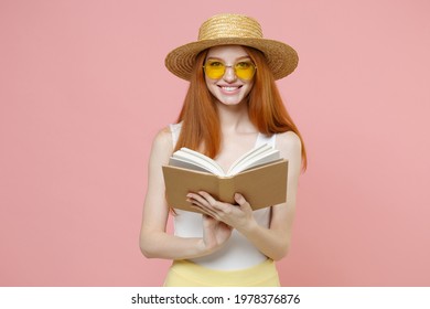 Young smart intelligent redhead cute smiling student woman 20s ginger wear straw hat glasses summer clothes holding reading interesting book isolated on pastel pink color background studio portrait - Powered by Shutterstock