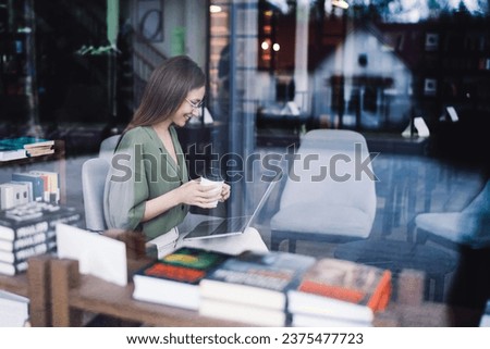 Young smart lady using laptop in bookstore