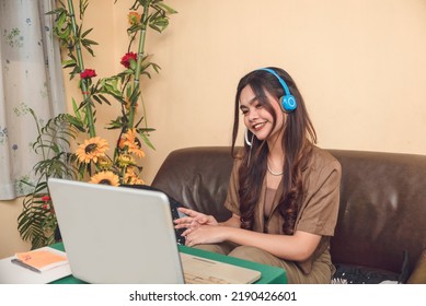 A Young Smart Lookingasian Woman Wearing Brown Smart Casual Attire In Communication Online Over The Internet.