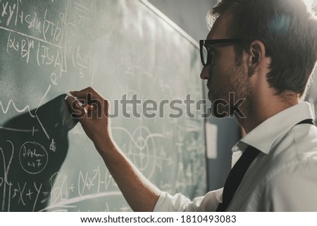 Young smart mathematician drawing math formulas on the chalkboard and thinking: he is solving problems and discovering new theories