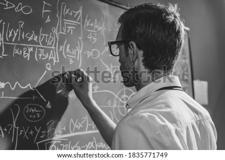 Young smart mathematician drawing math formulas on the chalkboard and thinking: he is solving problems and discovering new theories