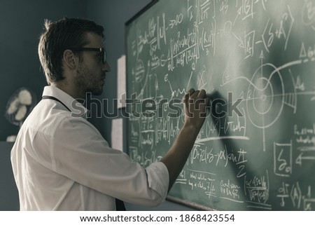 Young smart mathematician drawing math formulas on the chalkboard and thinking: he is solving problems and discovering new theories